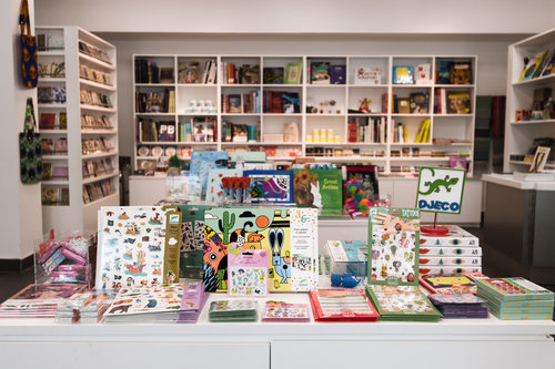 Image of various illustrated books at the front of the picture and shelves with other items of stock. Items on sale in the Glynn Vivian Art Gallery shop. Photo © Polly Thomas