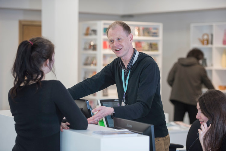 A member of staff giving information to a visitor at the reception of the Glynn Vivian Art Gallery