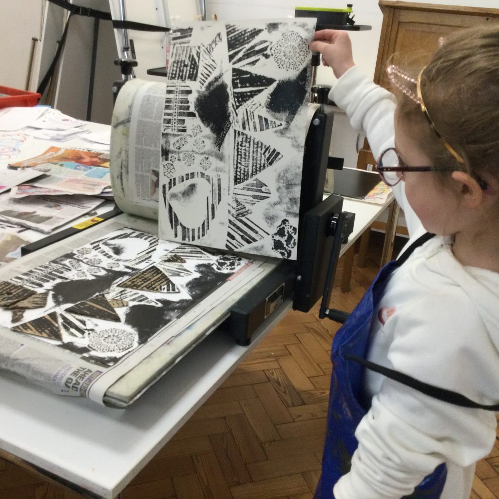 Child using the printing press to create a collagraph print