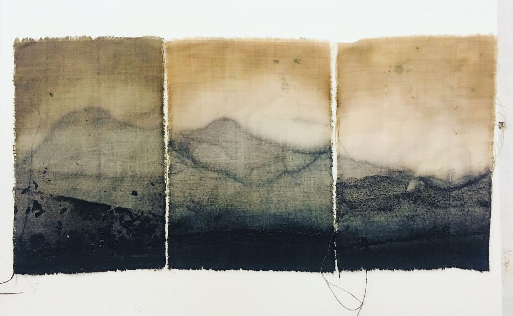 Three pieces of cloth, which have been dyed using dark coloured natural dyes