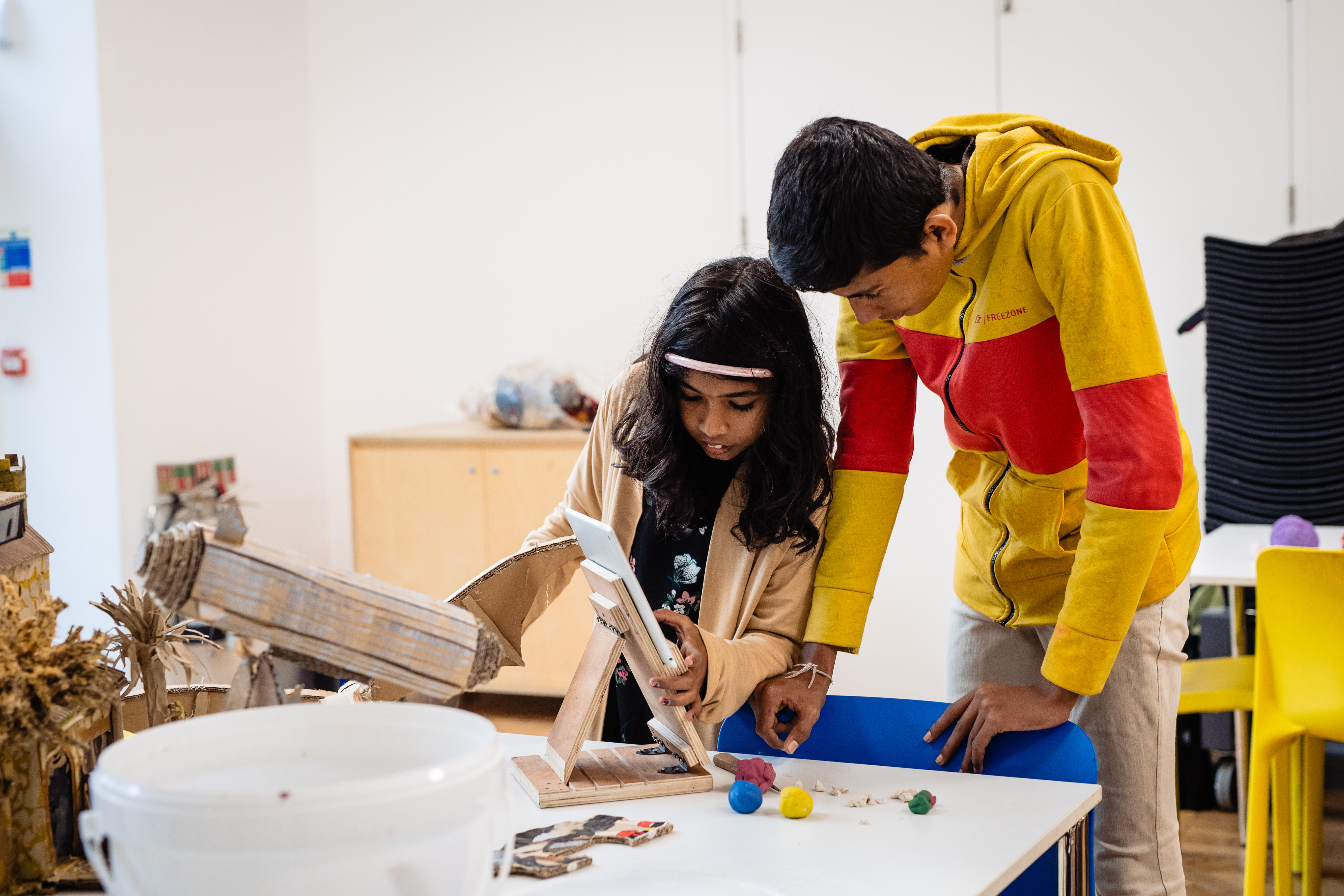 Two children using a tablet to create an animation from cardboard sculptures