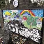 A picture of a mosaic mounted on a wall outside