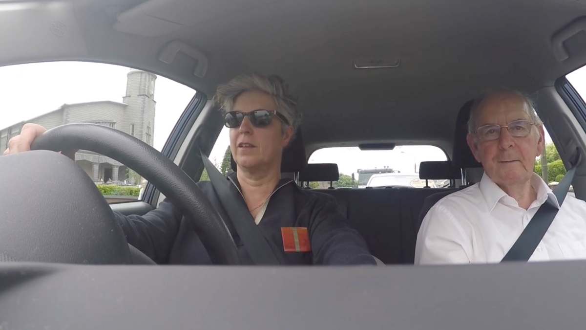 Two people sitting in a car. Image is taken from the dashboard.
